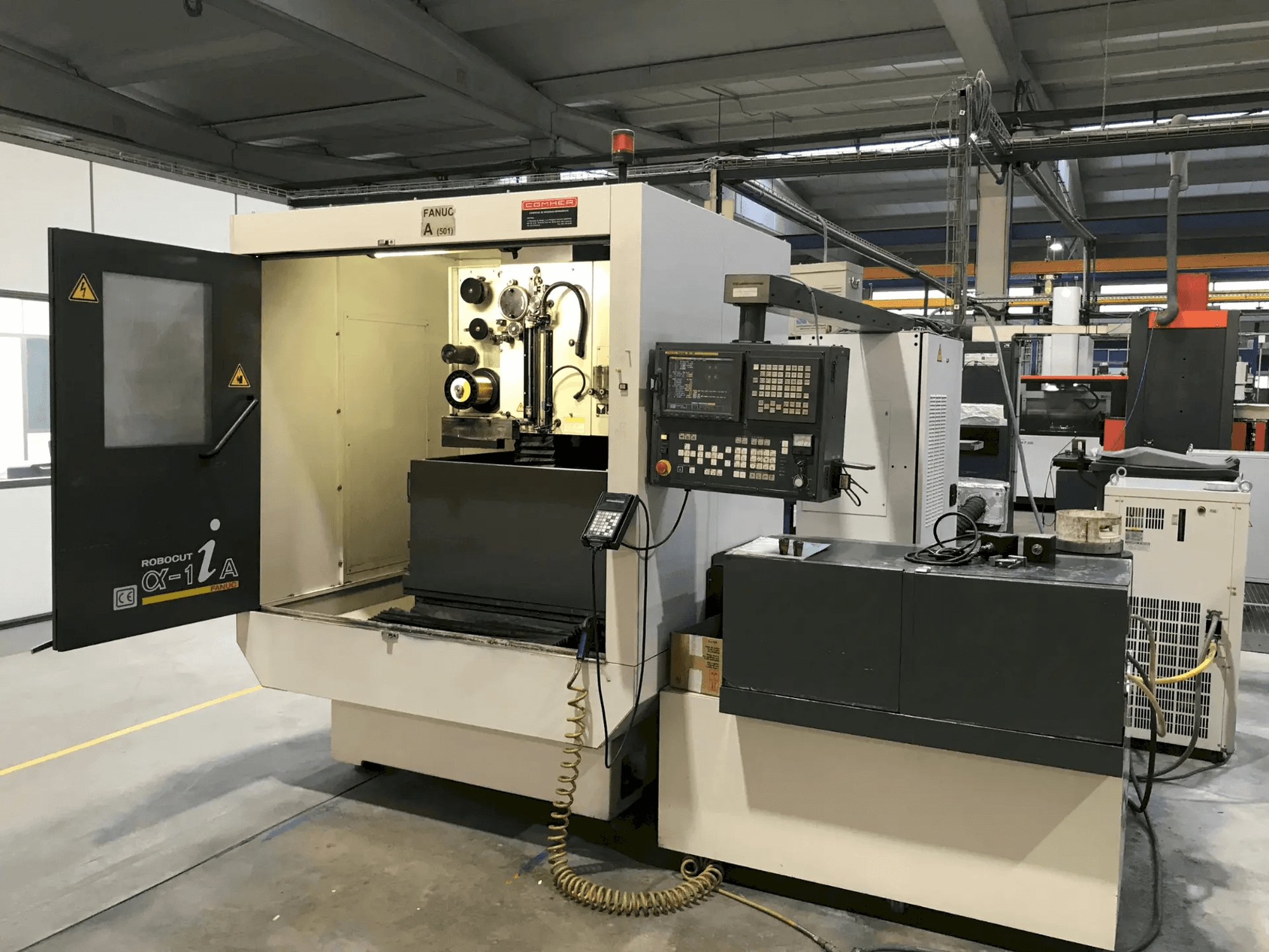 Centre d'usinage vertical Mazak, porte ouverte permettant de voir les outils et les commandes, vue de profil, destiné aux applications d'usinage de précision.